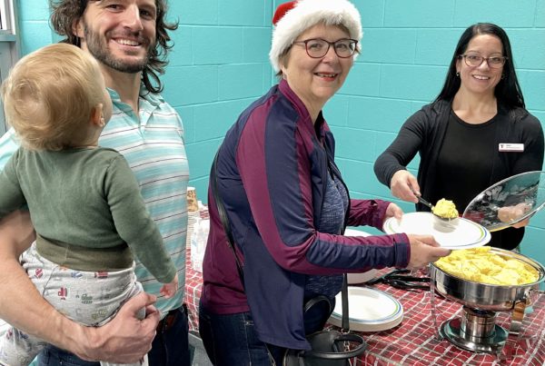 United Way Volunteer Treasurer Kathy Sitter is served breakfast by Nikki Tremblay at the Sarnia Family YMCA breakfast fundraiser with YMCA General Manager Paul Skuza holding his son Hugo