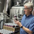 United Way board member Alan Blahey poses with three cases of United Way branded beer
