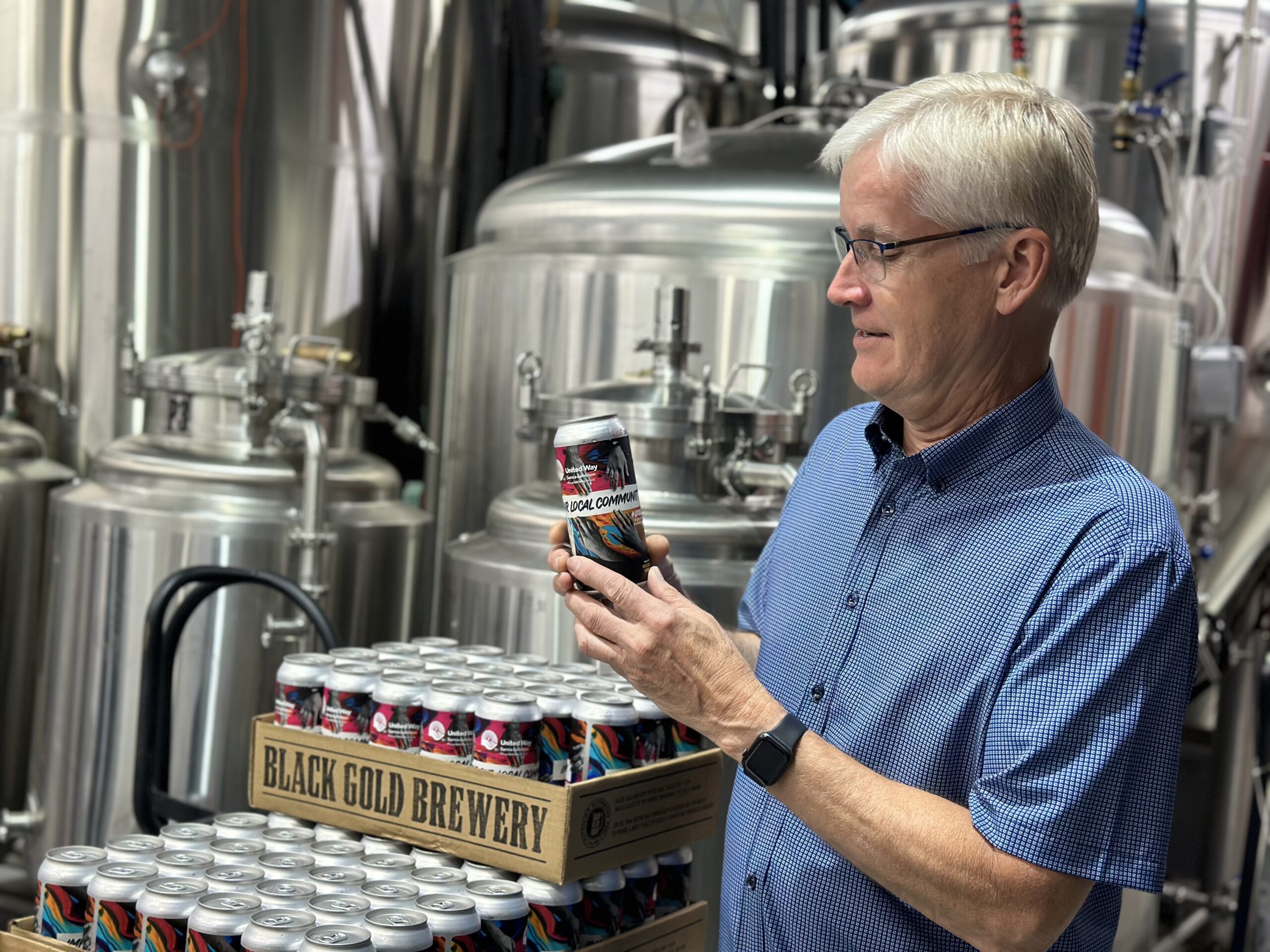 United Way board member Alan Blahey poses with three cases of United Way branded beer
