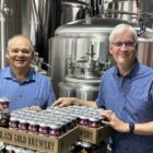 Executive Director, Dave Brown, and board member, Alan Blahey pose in front of several cases of United Way branded beer at Black Gold Brewery