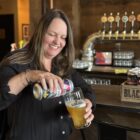 Board member Krista pours a glass of United Way branded beer at Black Gold brewery